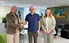 Tre personer i kontorlounge, to gir hverandre håndtrykk.