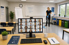 20 ansikter vises på en PC-skjerm. Skjermen står i et klasserom. Foran i klasserommet står en kvinne og demonstrerer mopping. I bildet er også elementer som viser at opplæringen har å gjøre med renhold og med avfallshåndtering.