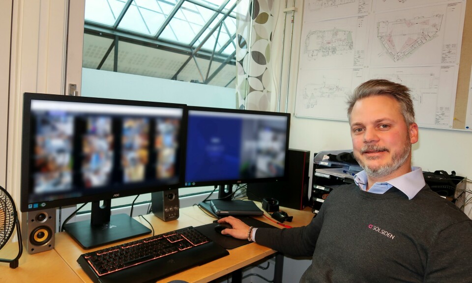 Henrik Finne sitter ved en pult med flere PC-skjermer med sladdet innhold.
