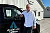 Bjørnar Pettersen ved siden av en bil med logoen til Assistent Partner på
