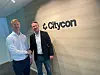 Håkon Tuv Dalland og Henrik Andersen tar hverandre i hånda foran et Citycon-skilt